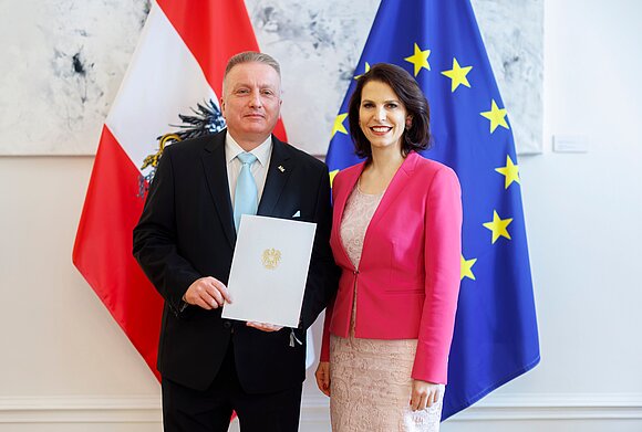 Ein Mann und eine Frau stehen nebeneinander und halten ein Dokument in den Händen.