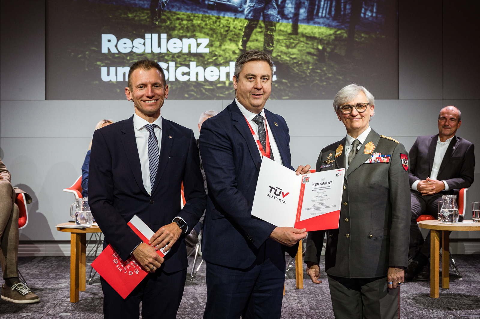 Drei Personen bei Zertifikatsübergabe.