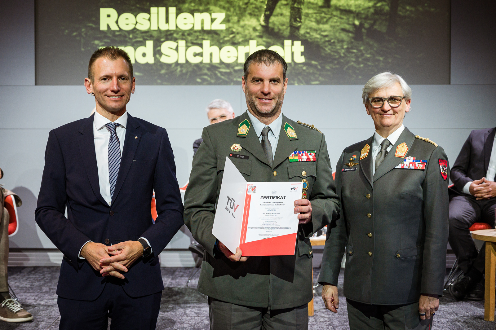 Drei Personen bei Zertifikatsübergabe.