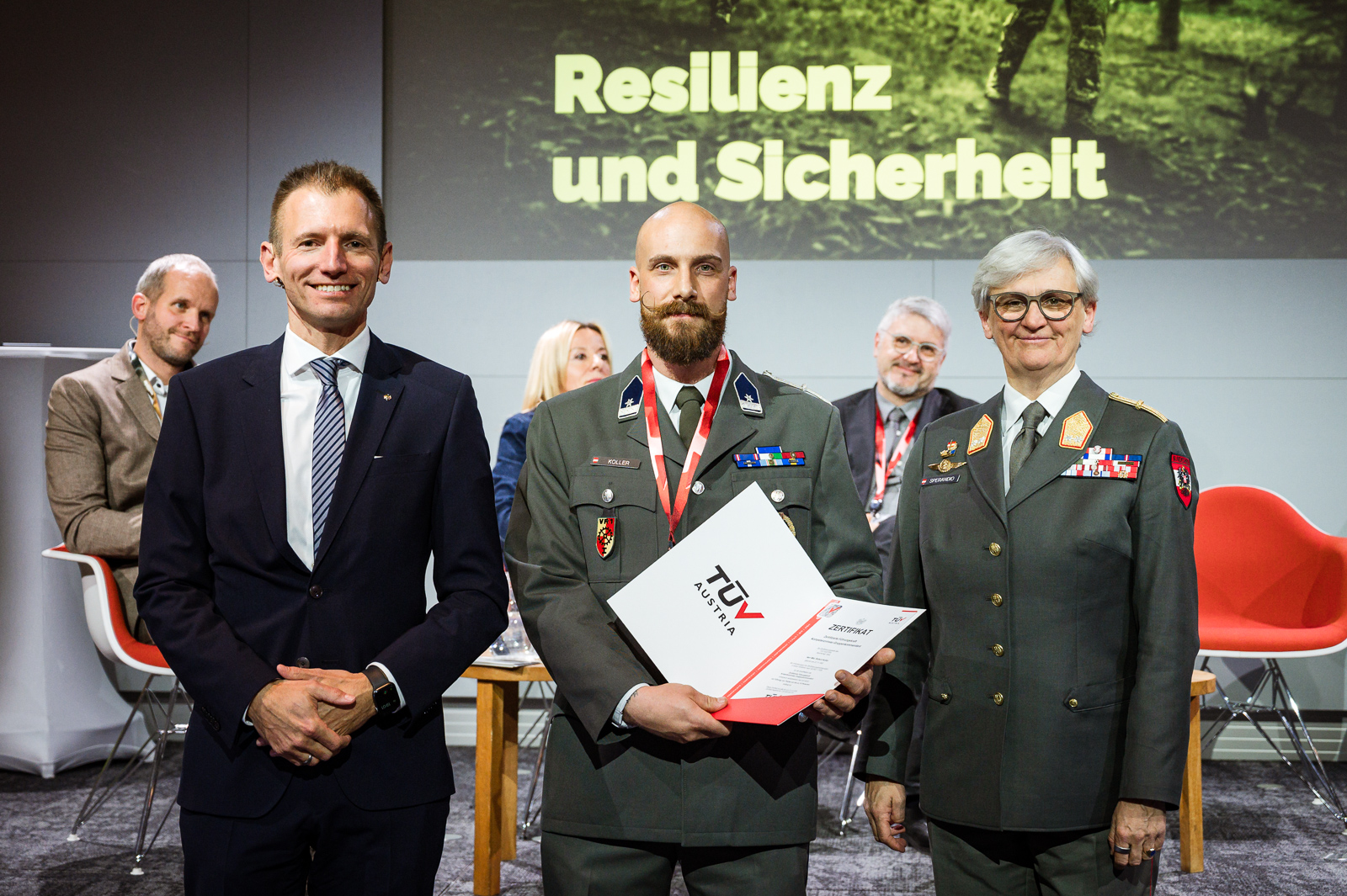 Drei Personen bei Zertifikatsübergabe.